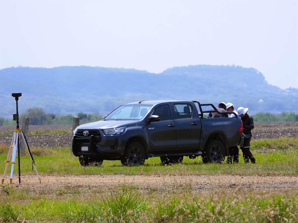 Brigada de campo con estación total y vehículo de trabajo en un predio en estudio